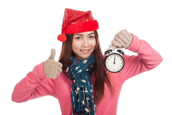 Asian girl with red christmas hat show thumbs up and alarm clock — Stock Photo, Image
