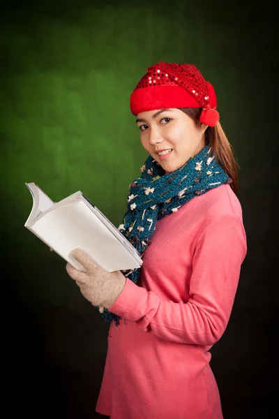 Asiatisches Mädchen mit rotem Weihnachtsmütze liest ein Buch — Stockfoto