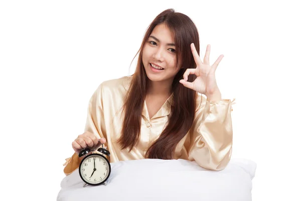 Happy Asian girl  show OK  with pillow and alarm clock — Stock Photo, Image