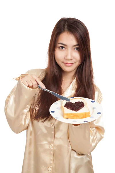 Asiatin im Pyjama mit Brot und herzförmiger Beerenmarmelade — Stockfoto