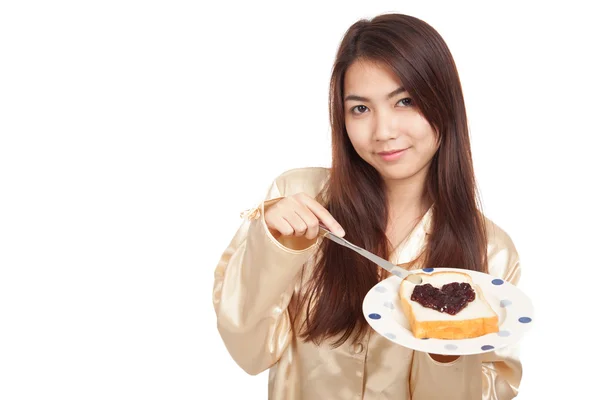 Asiatin im Pyjama mit Brot und herzförmiger Beerenmarmelade — Stockfoto