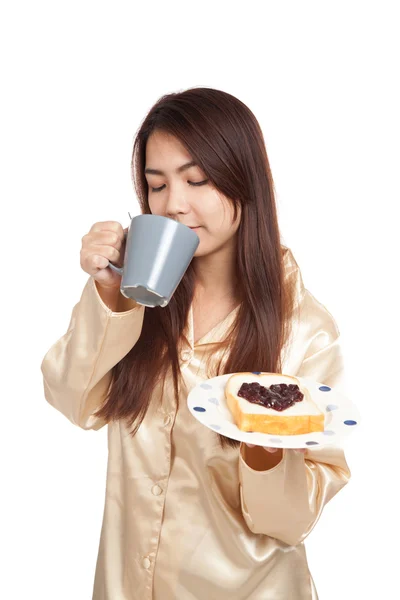 Asiatin im Schlafanzug mit Kaffee und herzförmiger Marmelade auf Brot — Stockfoto