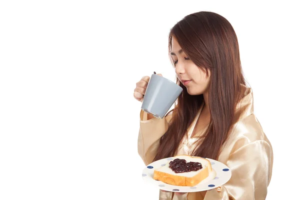 Asian woman in pajamas with coffee and heart shape jam on bread — Stock Photo, Image