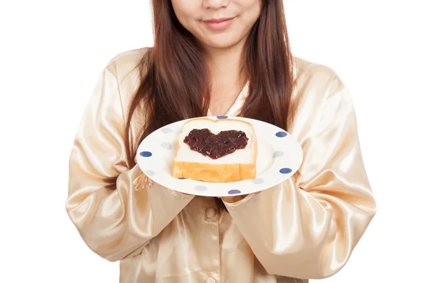 Ázsiai nő pizsamában, kenyérrel és szív alakú bogyó lekvárt — Stock Fotó
