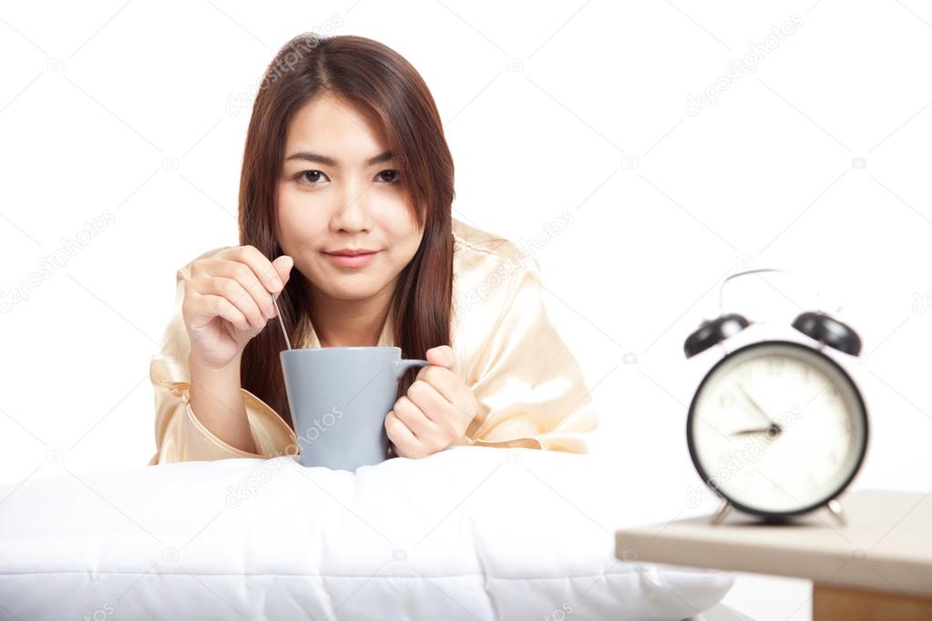 Happy Asian girl  wake up  with alarm clock and  coffee cup