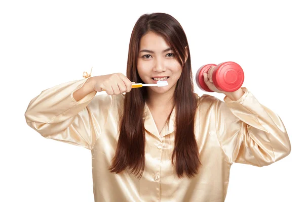 Asian woman in pajamas with toothbrush and red dumbbell — Stock Photo, Image