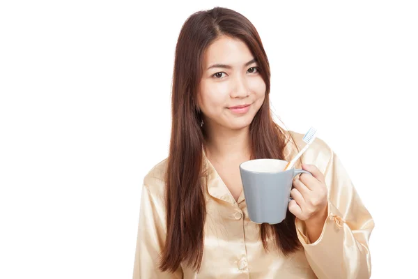 Asian woman in pajamas with toothbrush in mug — Stock Photo, Image