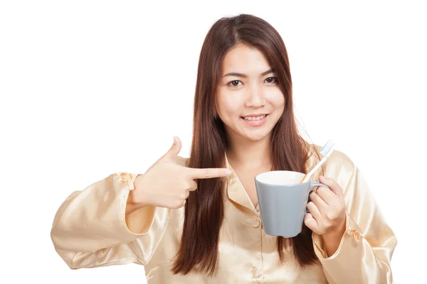 Asian woman in pajamas point to toothbrush in mug — Stock Photo, Image