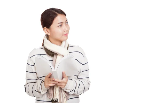 Hermosa chica asiática con bufanda leer un libro mirar hacia otro lado y sonreír — Foto de Stock