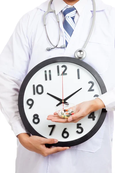 Asian male doctor show a clock and pills — Stock Photo, Image