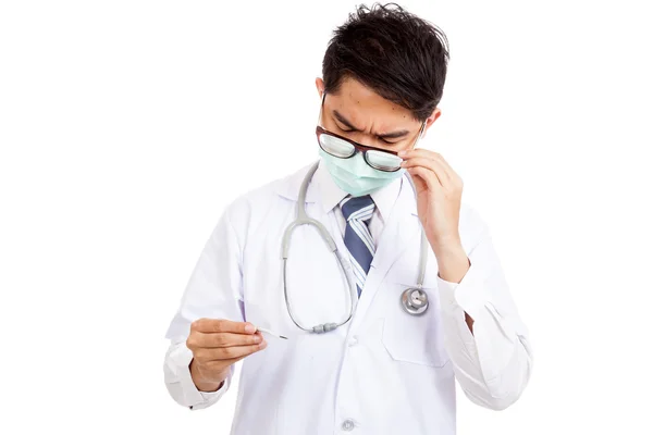 Aziatische mannelijke arts slijtage masker met ernstige gezicht kijken naar thermome — Stockfoto