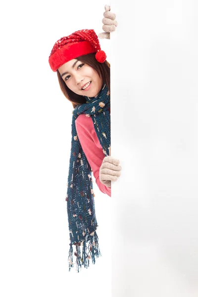 Asian girl with red christmas hat peeking from behind blank boar — Stock Photo, Image