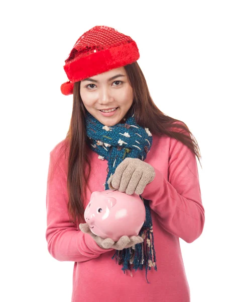 Asiatisches Mädchen mit rotem Weihnachtsmütze, Münze und Sparschwein — Stockfoto