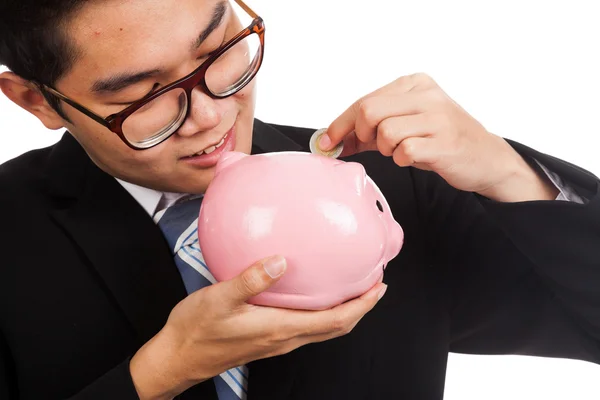 Asiático empresário sorriso colocar uma moeda para um rosa porquinho banco — Fotografia de Stock