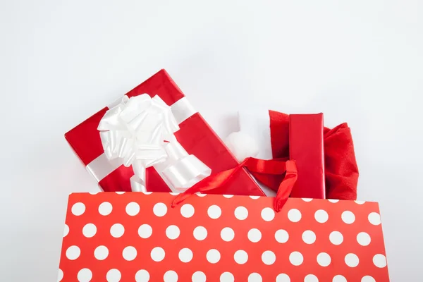 Cajas de regalo rojas y sombrero de Navidad en bolsas de compras —  Fotos de Stock