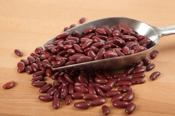 Frijoles rojos con cuchara sobre mesa de madera —  Fotos de Stock