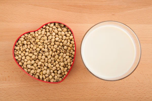 Sojamjölk i glas med sojabönor i hjärta form låda — Stockfoto