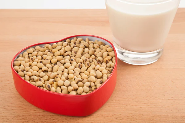 Soy milk in glass with soybeans in heart shape box — Stock Photo, Image