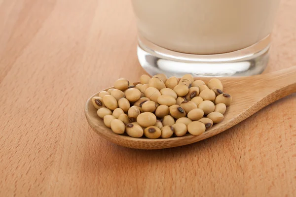 Soy milk in glass with soybeans and wooden spoon — Stock Photo, Image
