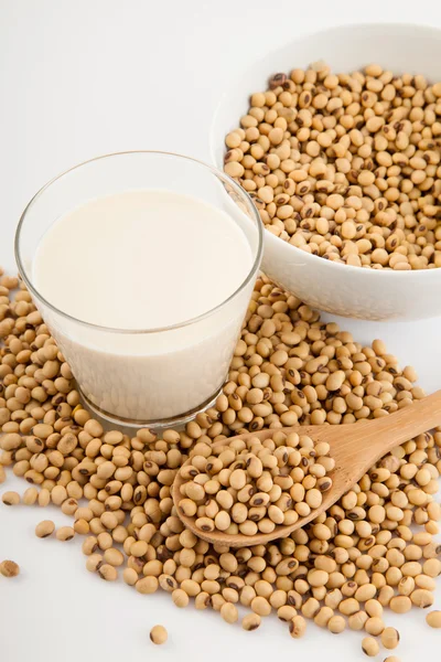 Soy milk in glass with soybeans and wooden spoon — Stock Photo, Image