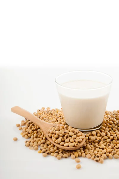 Soy milk in glass with soybeans and wooden spoon — Stock Photo, Image