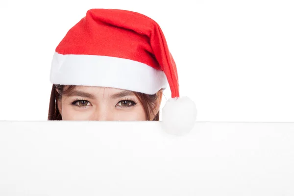 Menina asiática com chapéu vermelho santa espreitando atrás de uma placa em branco — Fotografia de Stock