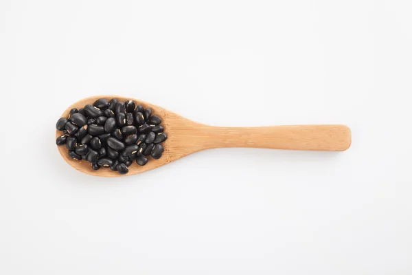 Черные бобы с деревянной ложкой — стоковое фото