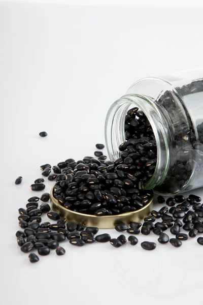 Schwarze Bohnen im Glas auf weißem Tisch mit Deckel — Stockfoto