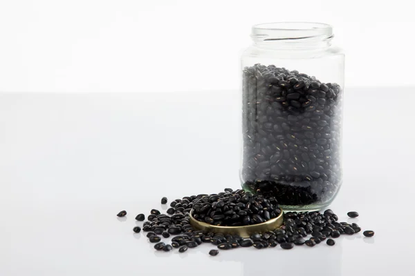 Zwarte bonen in een pot op witte tafel met deksel af — Stockfoto