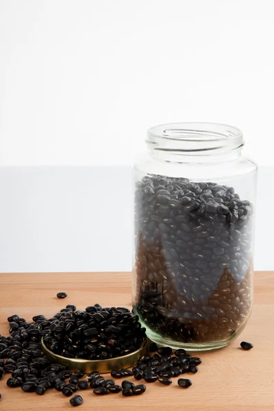 在木桌上的一个罐子里的黑豆 — 图库照片