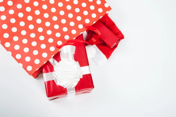 Červené dárkové krabičky a a vánoční klobouk v nákupní tašky — Stock fotografie