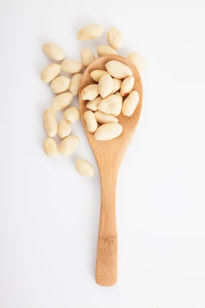 Amendoins descascados com colher de madeira no fundo branco — Fotografia de Stock