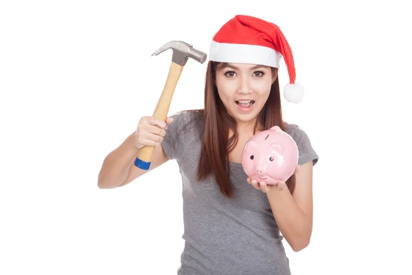 Asiatisk tjej med röd santa hatt hålla hammare och rosa spargris — Stockfoto