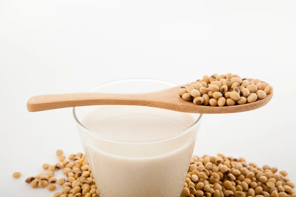 Soy milk in glass with soybeans and wooden spoon — Stock Photo, Image