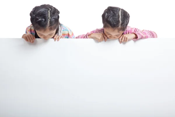 Asiatische Zwillingsschwestern hinter leeren Plakatwänden — Stockfoto