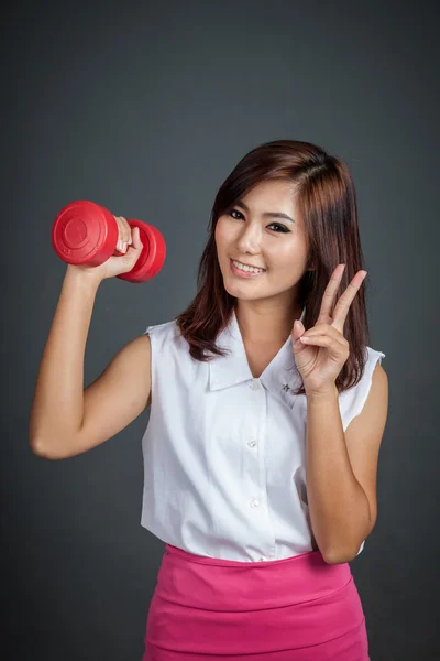 Happy Asian girl hold a dumbbell show vicrtory sign — Stock Photo, Image