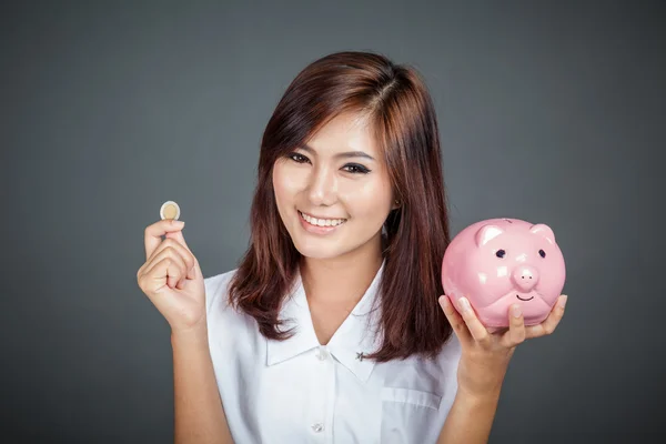Bella ragazza asiatica con una moneta e scatola di soldi rosa maiale — Foto Stock
