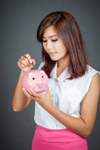 Güzel Asyalı kız bir pembe domuz para kutusuna koydu — Stok fotoğraf
