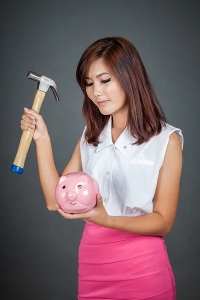 Beautiful Asian girl about to hit money box with hammer — Stock Photo, Image