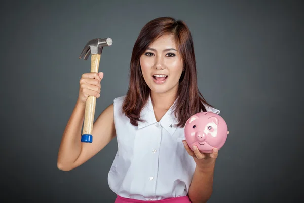 Feliz hermosa chica asiática con caja de dinero de cerdo rosa y martillo — Foto de Stock