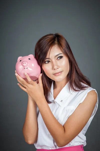 Beautiful Asian girl wonder how much money in piggy bank — Stock Photo, Image