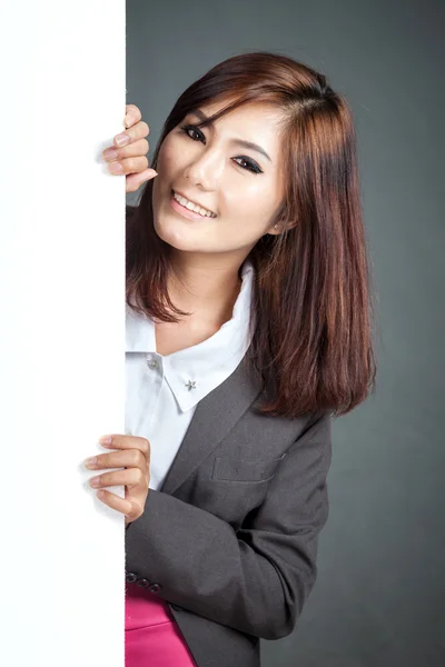 Asiática mujer de negocios de pie detrás de un banner en blanco y sonrisa —  Fotos de Stock