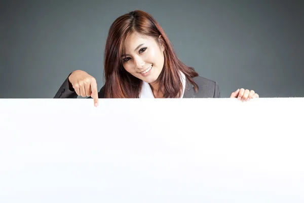 Asiática mujer de negocios de pie detrás de un cartel en blanco, apuntar hacia abajo —  Fotos de Stock