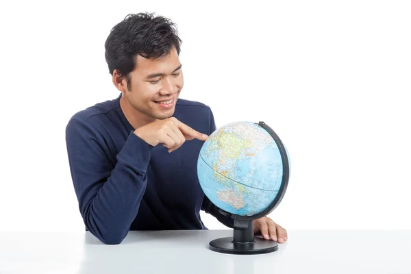 Homem asiático procurando em um globo mundial — Fotografia de Stock