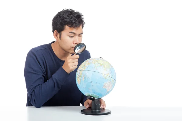 Asiático hombre uso lupa búsqueda en un mundo globo — Foto de Stock