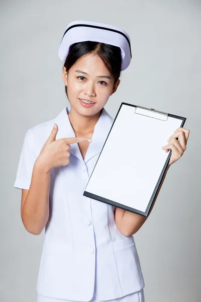 Joven asiática enfermera punto a blanco papel en portapapeles —  Fotos de Stock