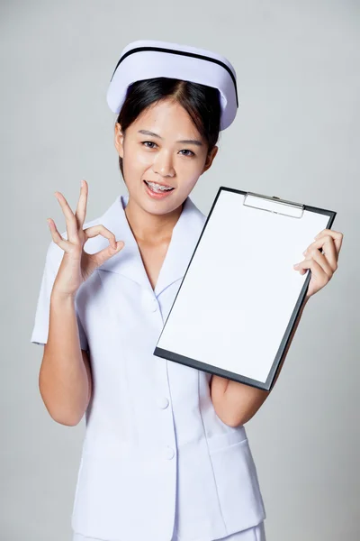 Young Asian nurse show OK with blank paper on clipboard — Stock Photo, Image