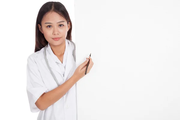 Jovem asiática médica atrás do ponto de sinal em branco com uma caneta — Fotografia de Stock