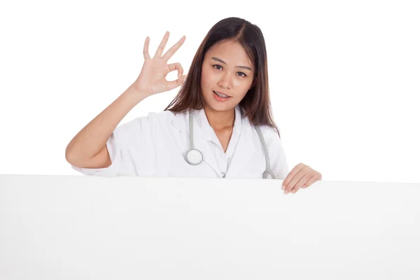 Junge asiatische weibliche Arzt zeigen ok Zeichen hinter leeren weißen Billb — Stockfoto