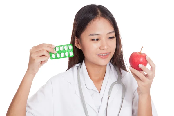 Jonge Aziatische vrouwelijke arts met pillen en apple — Stockfoto